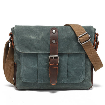 Vintage blue-grey waxed canvas messenger bag with premium leather accents, front view.