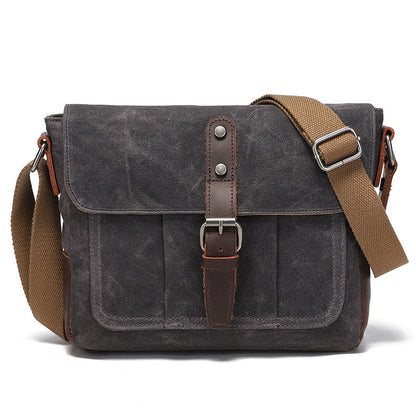 Vintage charcoal grey waxed canvas messenger bag with brown leather strap detail, front view.