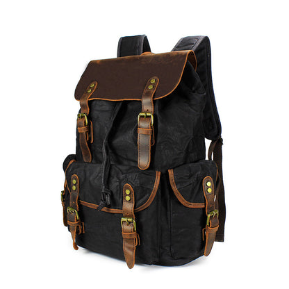 Front view of the black Vintage Waxed Canvas Multi-Pocket Rucksack, highlighting the sleek dark canvas paired with genuine leather straps and brass hardware.